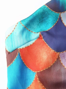 Close-up of mermaid scale print on satin fabric with colorful geometric patterns