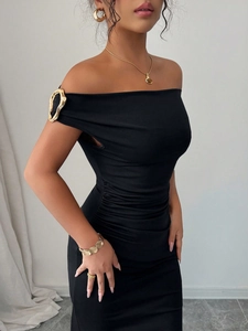 Detail of elegant black off-shoulder dress featuring a unique gold metal buckle