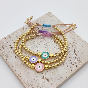 Three colorful evil eye beaded bracelets with gold accents on a beige stone plate