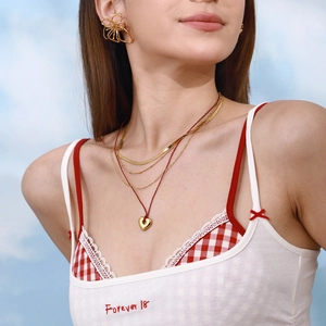 Layered gold stainless steel necklaces with heart pendant and red cord on a model