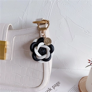 Detail of leather camellia keychain with gold coin charm on white crocodile handbag