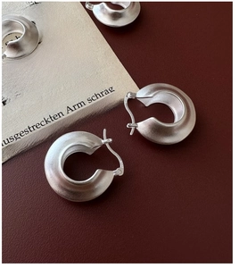 Macro shot of S925 sterling silver hoop earrings with a brushed matte finish on a dark base