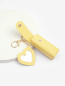 Detail of yellow PU leather lipstick holder case with heart-shaped mirror and gold snap