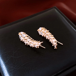 Macro shot of gold wheat ear earrings with zircon and pearls on black leather