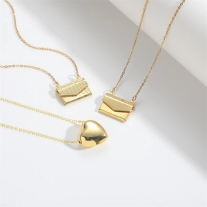 Detailed close-up of three gold necklaces with envelope and heart-shaped pendants