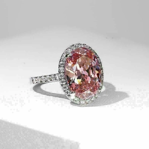 Pink oval cut gemstone ring in silver finish with pavé stones on a white background
