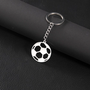 Polished stainless steel soccer ball pendant keychain on premium black leather surface