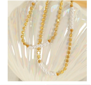 Macro shot of minimalist gold disc beads and glossy freshwater pearls on a necklace