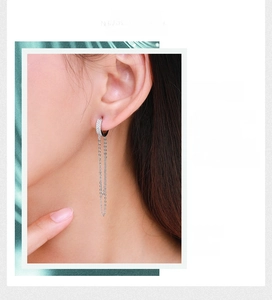 Détail de boucles d'oreilles longues à pampilles en argent avec micro-strass sur l'oreille