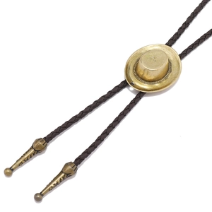 Detail of vintage brass cowboy hat bolo tie pendant on brown braided leather cord