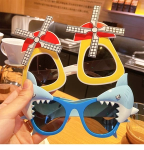 Detail of creative windmill and shark themed kids sunglasses held in a cafe setting