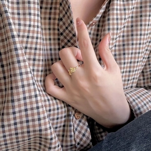 Detailed view of an adjustable golden rose flower ring worn by a model on index finger