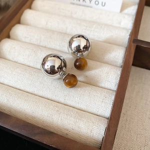 Detail of silver geometric stud earrings with amber translucent double ball design
