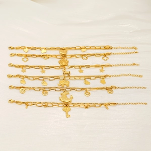 Detail of six double-layer gold bracelets with heart, star, and elephant charms on fabric