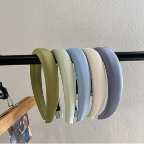 Detail of five handmade padded headbands in matte fabric pastel colors like olive and blue