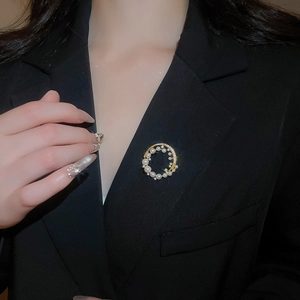 Detail of 18k gold plated brooch with pearls and zircon on a black blazer lapel