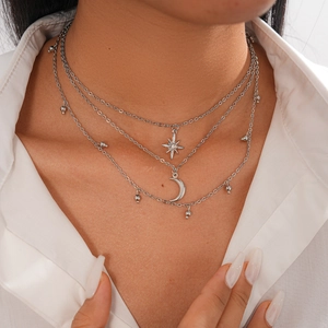 Detailed view of triple-layer silver necklace with star and moon charms on a model