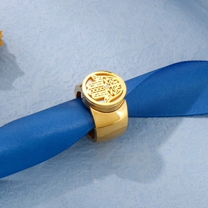 Detail of a gold Hamsa ring with a zircon center, displayed on blue silk ribbon.