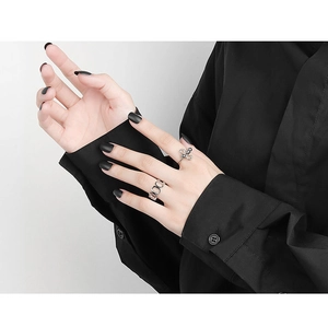 Detail view of silver metal adjustable rings with bear-shaped hollow cutout and knotted design
