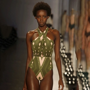 Detail of olive green halter swimsuit with geometric patterns and waist cutout on runway