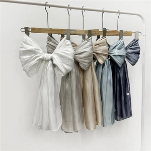 Variety of satin oversized bow accessories hanging in white, silver, and gold shades