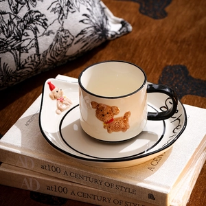 Detail view of a beige ceramic coffee cup set with embossed brown teddy dog and matching saucer