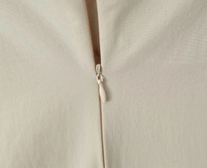 Detailaufnahme des verdeckten Reißverschlusses und der feinen Textur am beigen Kleid