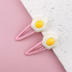 Detail shot of cute pink egg hair clips with white and yellow poached egg motifs