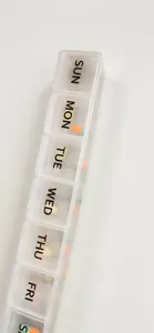 Detailed view of a 7-day pill organizer with black weekly labels and colorful capsules