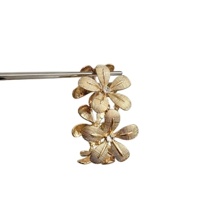 Gold floral cluster earrings with textured petals and rhinestones on white background