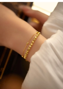 Detail of a gold double-layer beaded bracelet showing the textured finish on a model wrist