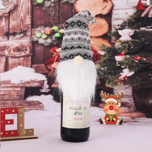 Close-up of a festive gnome wine bottle cover with a knitted hat and plush beard decoration