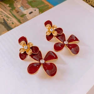 Close-up of red flower drop earrings with gold edging and sparkling crystals center