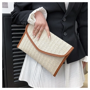 Close-up of handmade straw envelope clutch featuring V-pattern weave and leather trim