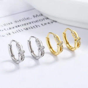 Detailed macro view of silver and gold twisted hoop earrings with micro-pave zircons