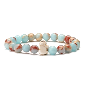 Detail of blue and brown stone beads with a white elephant charm on an elastic bracelet