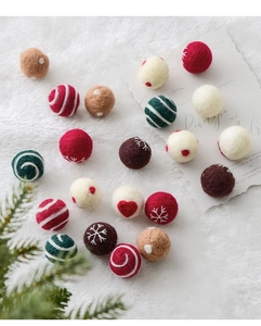 Detailed macro view of 3cm wool felt balls with snowflake and heart patterns for Christmas