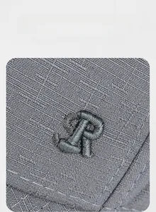 Close-up of deep gray baseball cap with ripstop texture and 3D metallic embroidery