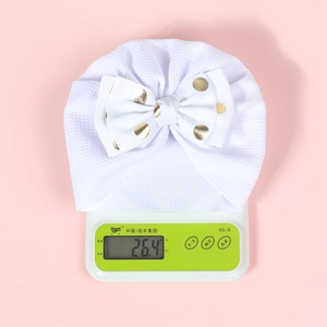 Weight measurement of white baby turban hat with golden polka dot bow detail