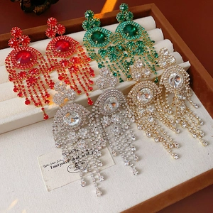 Dettaglio di orecchini vintage con nappe rosse, smeraldo, argento e oro con strass luminosi