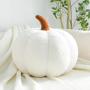 Close-up of white plush pumpkin pillow with lamb wool texture and brown stem detail
