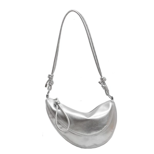 Silver metallic crescent dumpling bag with knotted shoulder strap on white background