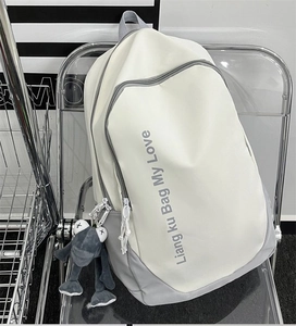 Close-up of minimalist cream and gray backpack featuring a cute frog plush charm detail