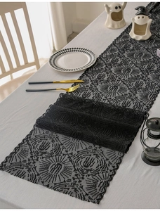 Detail of black lace spider web table runner with Halloween decor and ghost ornaments