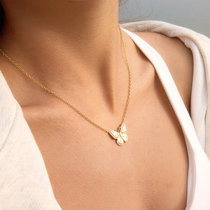 Gros plan d'un collier pendentif papillon doré avec cristaux sur le décolleté