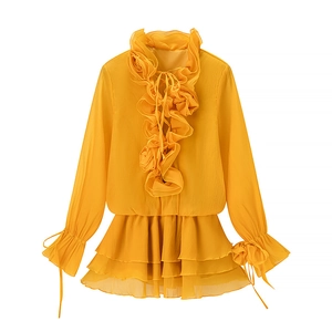 Detail of yellow chiffon dress featuring floral stand-up collar and layered ruffle hem