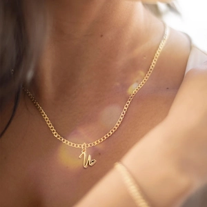 Close-up detail of a gold stainless steel cuban chain necklace with initial N heart pendant