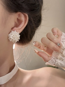 Close-up of elegant pearl cluster earrings with white beaded texture on model ear