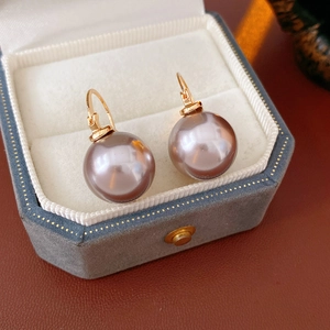 Close-up of grey pearl earrings with golden hoops in a premium velvet jewelry box