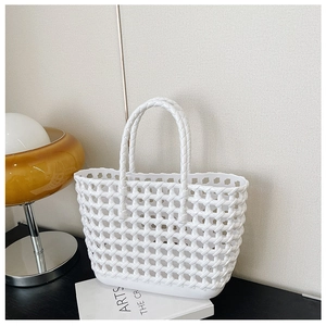 White hollow woven jelly tote bag displayed on a table with lamp and magazine